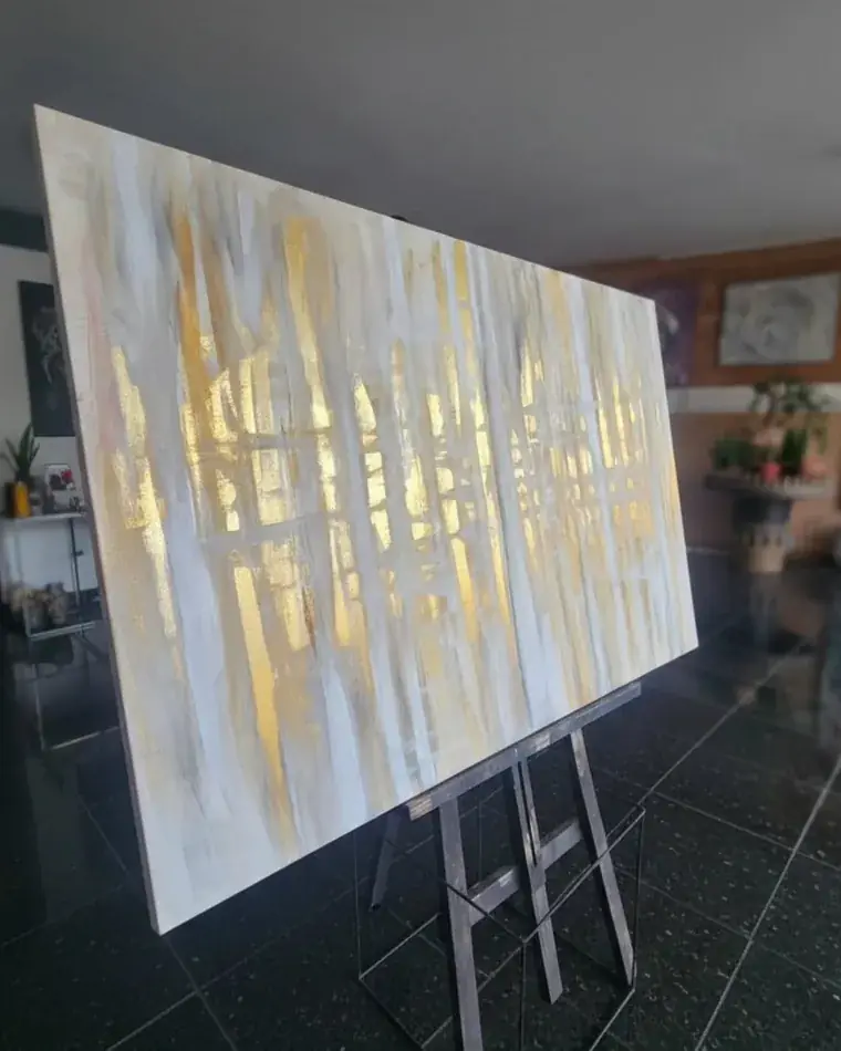 Obra abstrata em branco e dourado, no cavalete, pintada por Ale Baggio